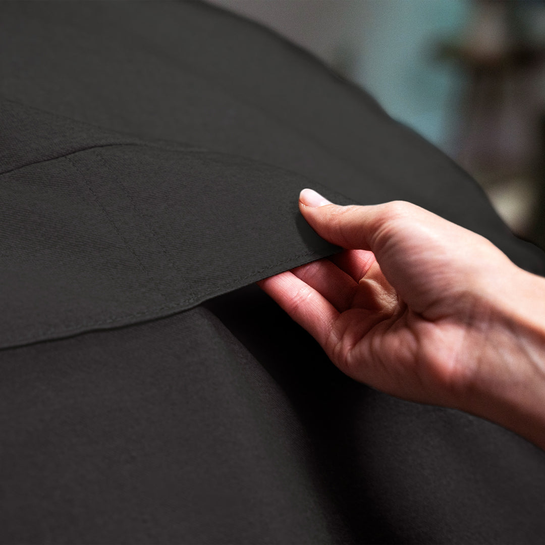 Hand holding a piece of black fabric #color_black-brushed-denim