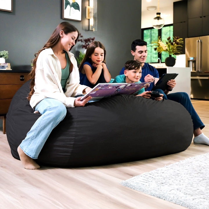 Family sitting on a large black bean bag in a modern living room. #color_black-brushed-denim