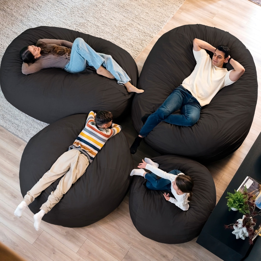 Four people relaxing on black bean bags in a living room. #color_black-brushed-denim