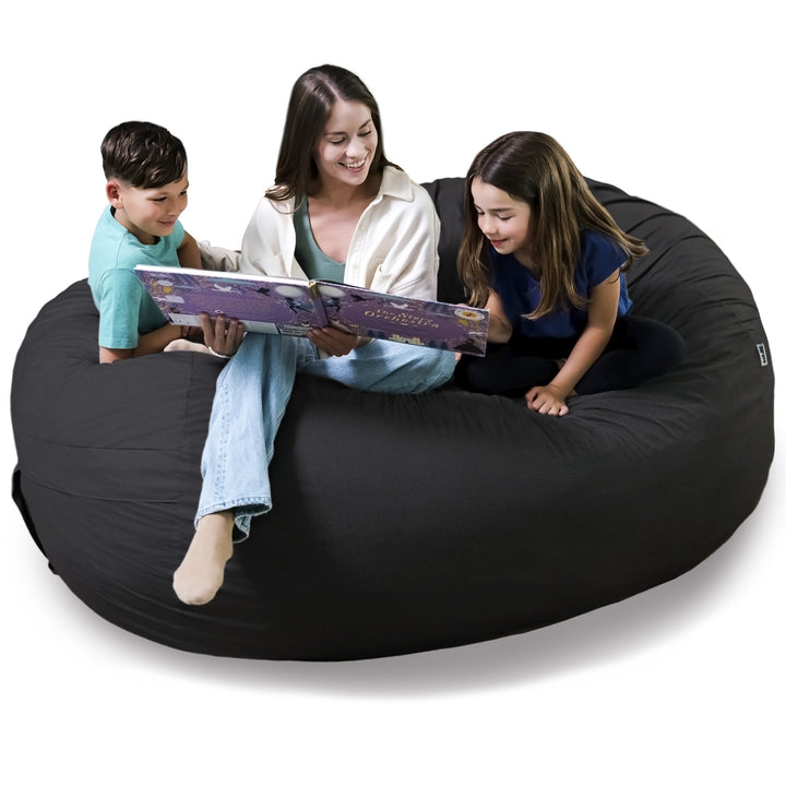 Woman and two children sitting on a large black bean bag reading a book together. #color_black-brushed-denim