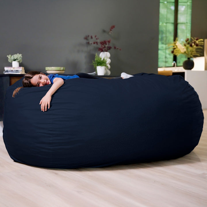 Person lying on a large navy bean bag in a room with plants and a window. #color_cobalt-brushed-denim