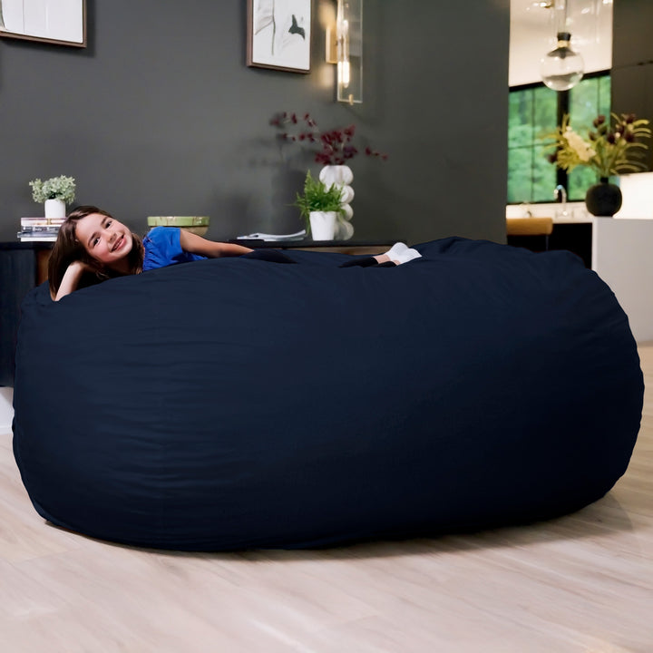 Woman lying on a large navy bean bag in a modern living room. #color_cobalt-brushed-denim