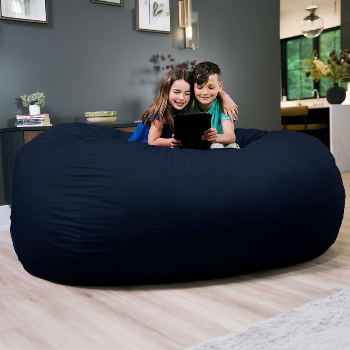 Two children sitting on a large navy bean bag in a living room. #color_cobalt-brushed-denim