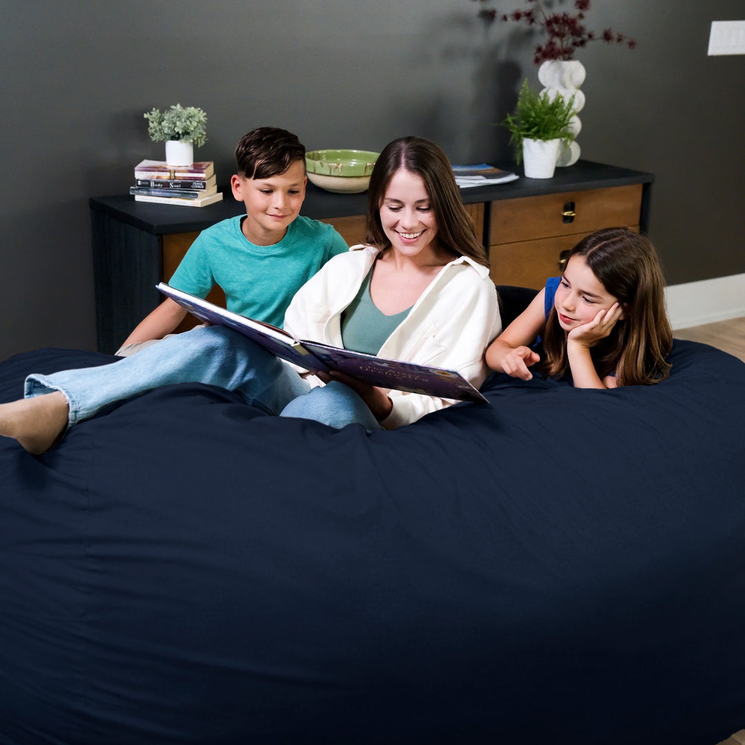 Woman reading a book to two children on a bed in a bedroom setting. #color_cobalt-brushed-denim