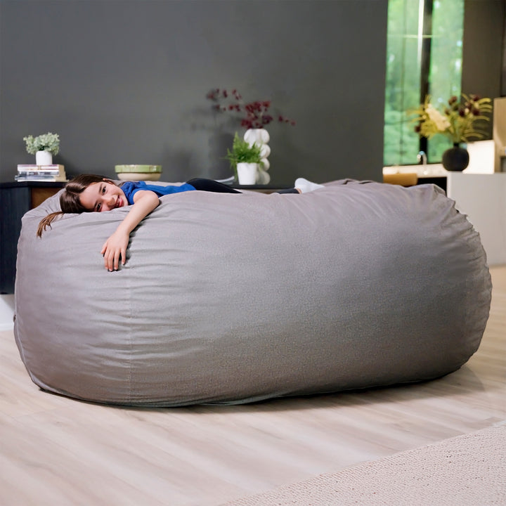 Person lying on a large gray bean bag in a modern living room. #color_fog-brushed-denim