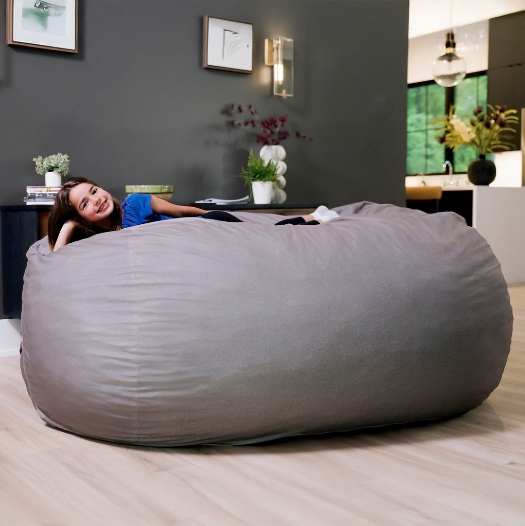Woman lying on a large gray bean bag in a modern living room. #color_fog-brushed-denim