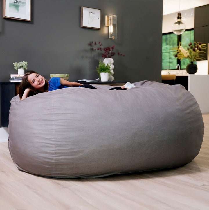 Woman lying on a large gray bean bag in a modern living room. #color_fog-brushed-denim