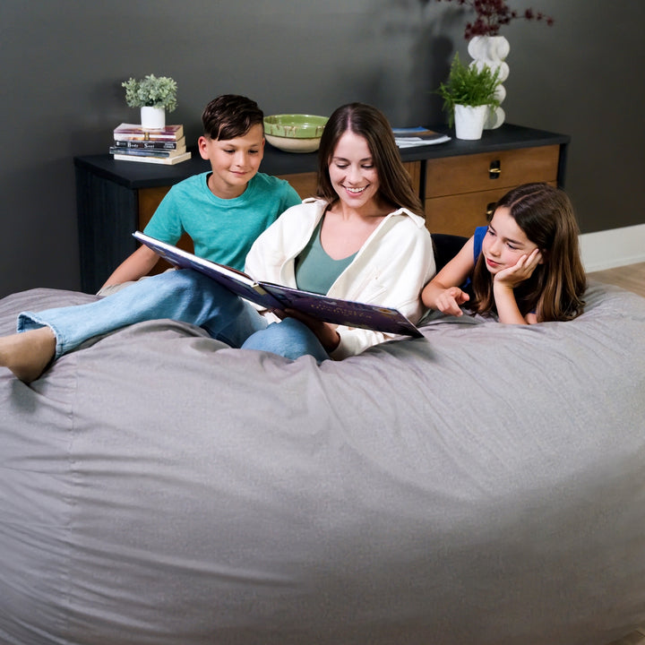 Woman reading a book to two children on a bean bag chair in a cozy room. #color_fog-brushed-denim