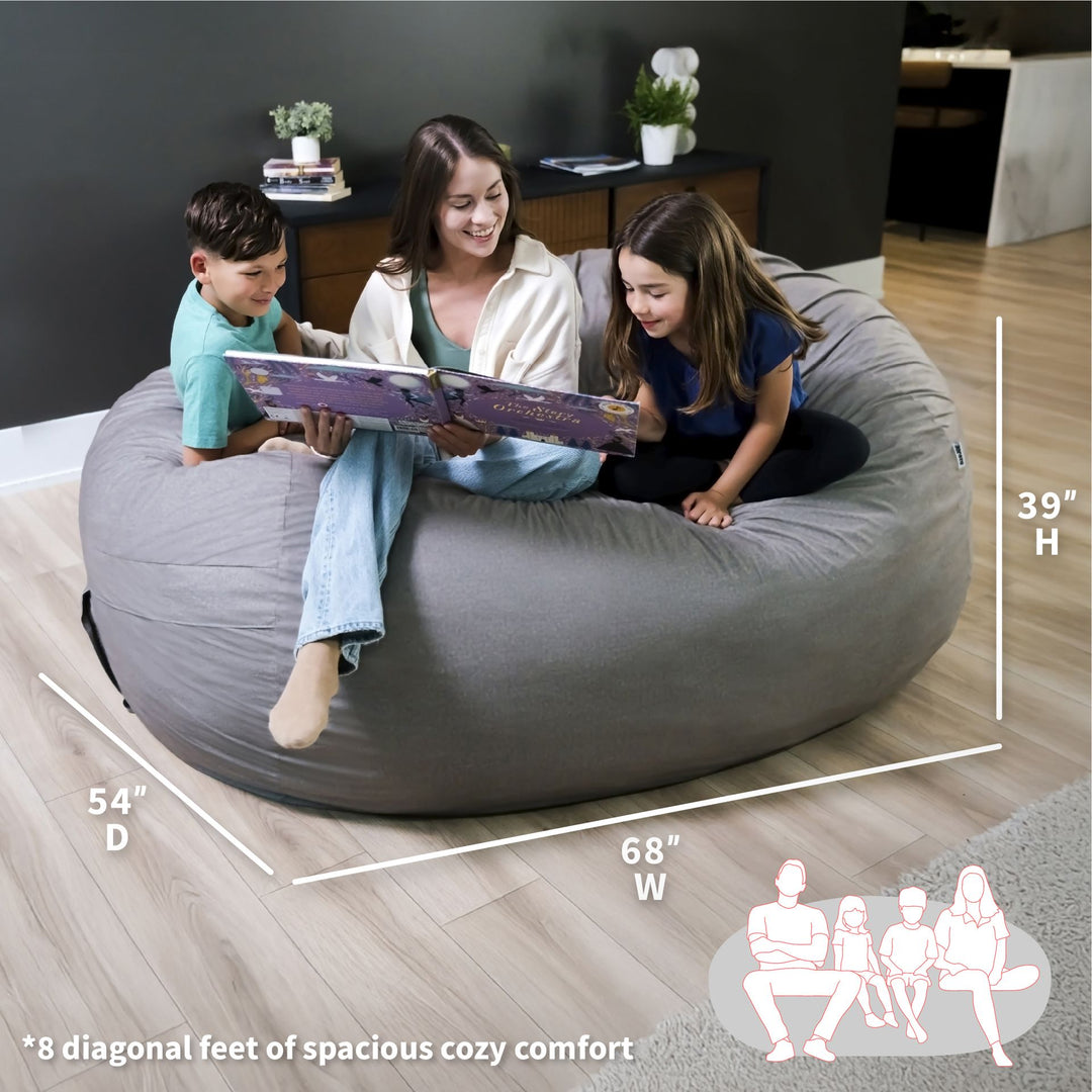 Woman and two children sitting on a large gray bean bag reading a book, with measurements displayed. #color_fog-brushed-denim