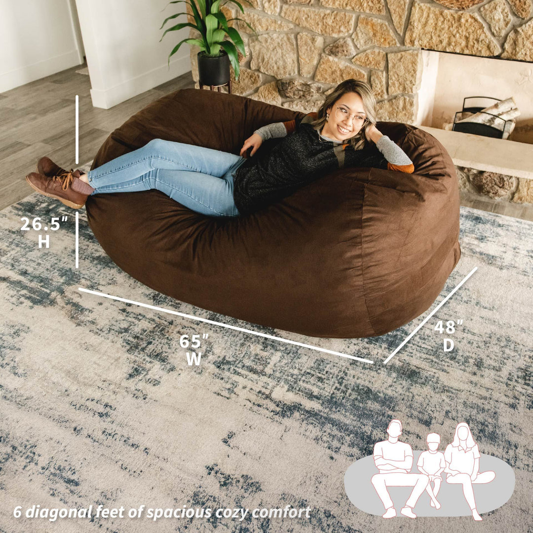 Woman sitting on a large brown bean bag chair with measurements and illustrations in a living room. #color_cocoa-brushed-denim