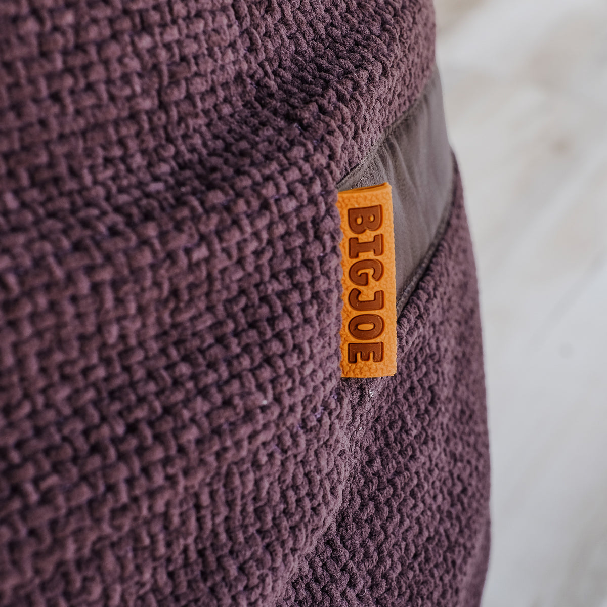 Close-up of a purple textured bean bag with a 'BIGJOE' label. 