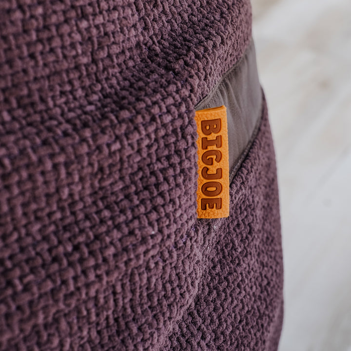 Close-up of a purple textured bean bag with a 'BIGJOE' label. #color_merlot-cloudweave