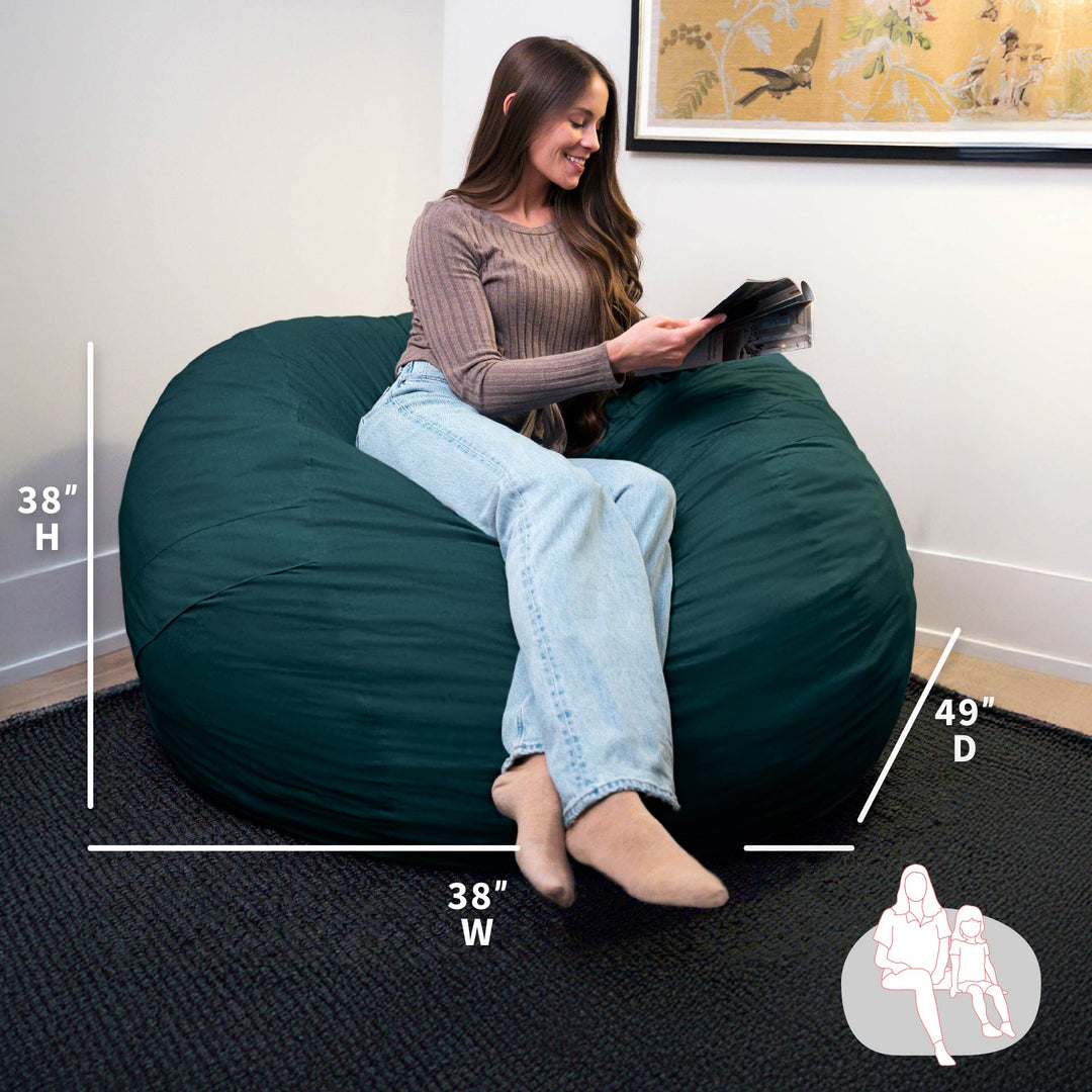 Woman sitting on a large green bean bag chair with measurements displayed. #color_deep-sea-velveteen
