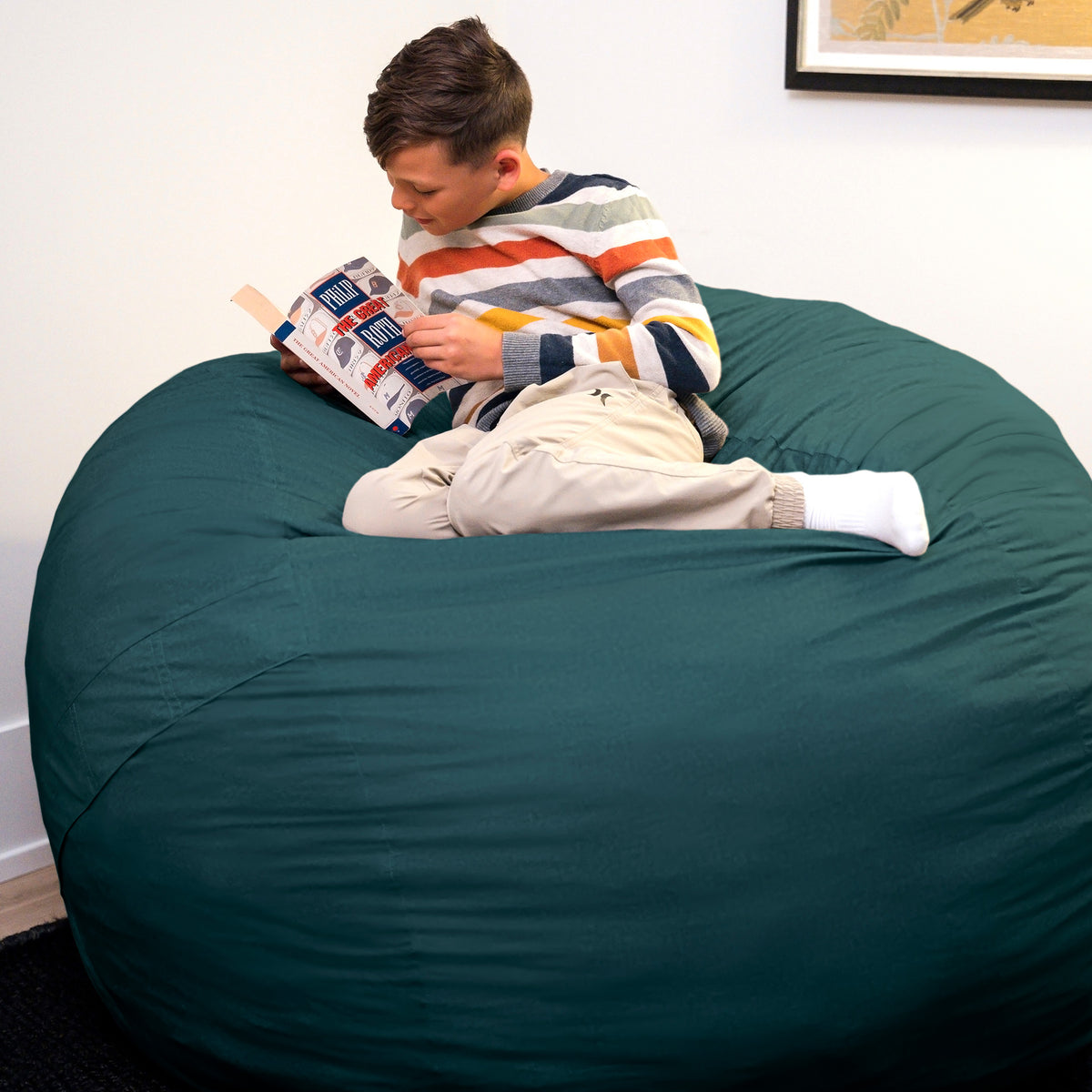 Person reading a book on a large teal bean bag chair. 