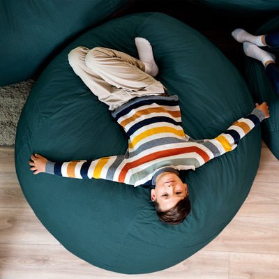 Child lying on a teal bean bag chair with striped sweater 