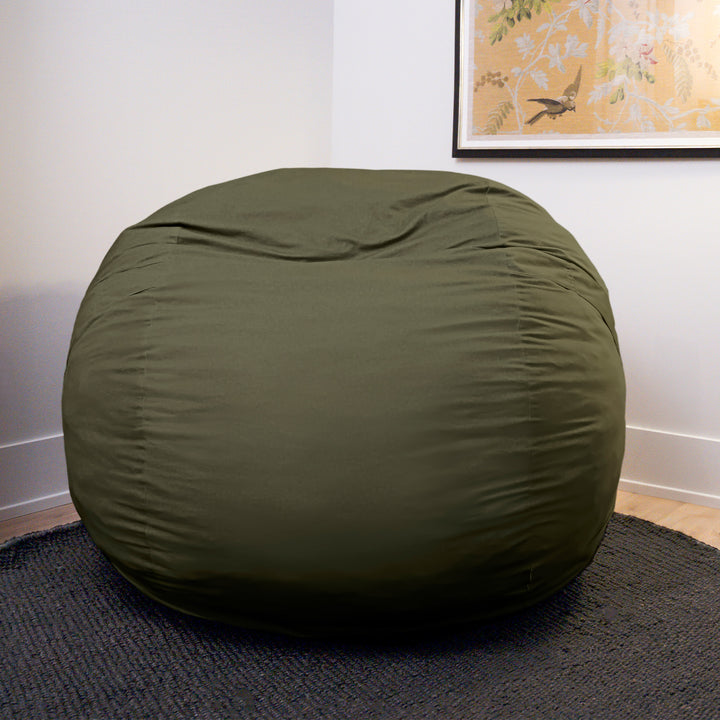 Green bean bag chair on a dark rug with a framed picture in the background #color_forest-green-velveteen