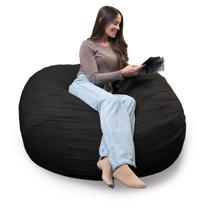 Woman sitting on a black bean bag chair reading a book against a white background #color_black-brushed-denim
