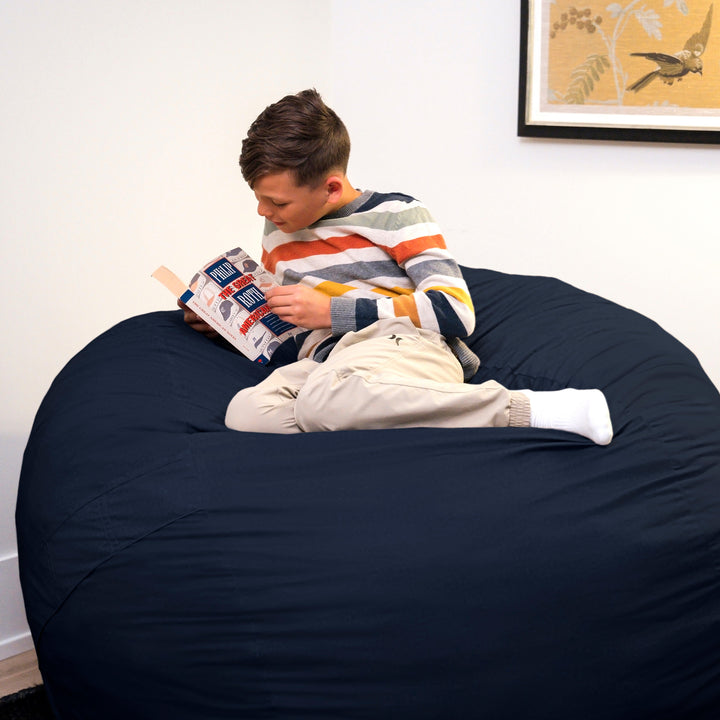 Person reading a book on a large navy bean bag chair. #color_cobalt-brushed-denim