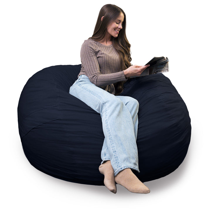 Woman sitting on a large navy bean bag chair reading a book. #color_cobalt-brushed-denim