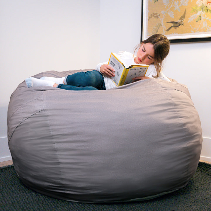 Person reading a book inside a large gray bean bag chair. #color_fog-brushed-denim