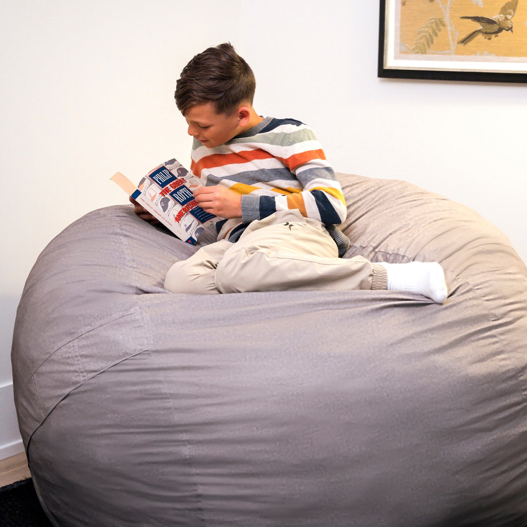 Person reading a book on a large gray bean bag chair. #color_fog-brushed-denim