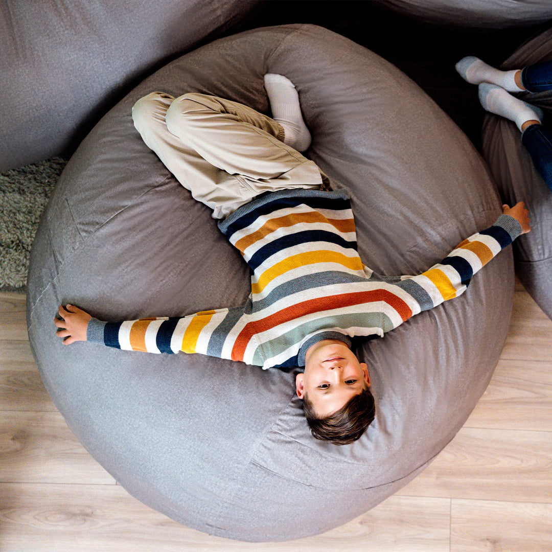Child playing on a large bean bag chair indoors #color_fog-brushed-denim