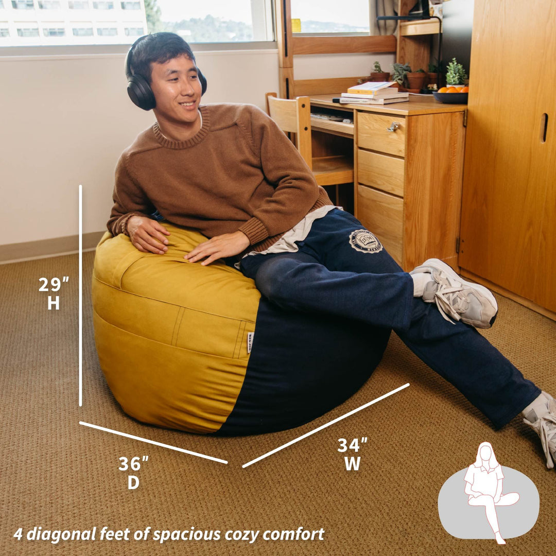Person sitting on a bean bag chair with dimensions displayed, in a room setting.  #color_blue-gold-brushed-denim