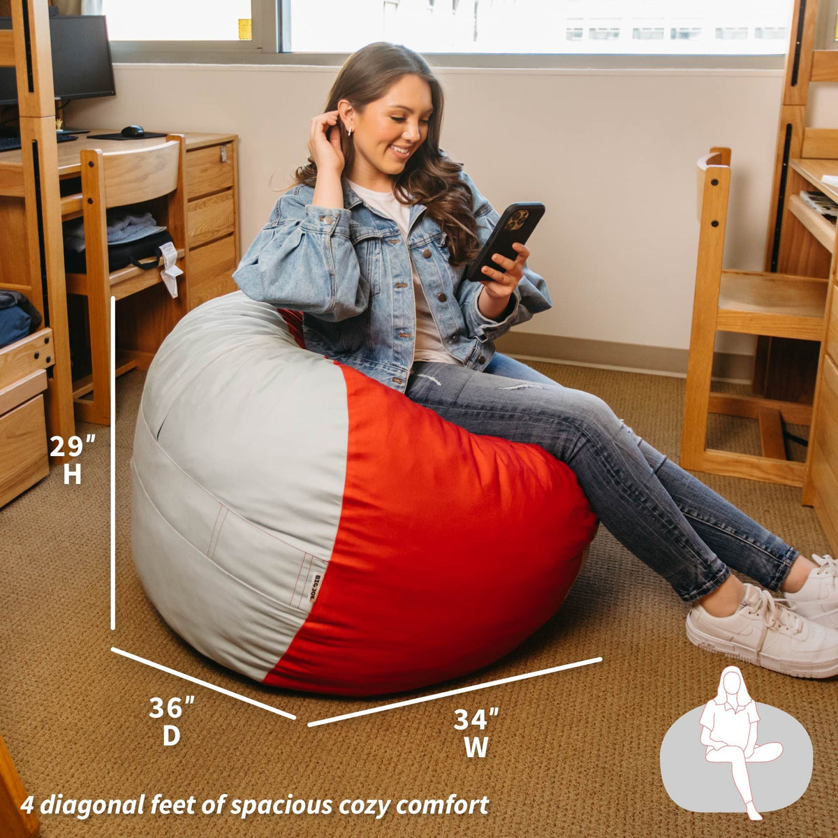 Person sitting on a red and gray bean bag chair in a room with desks and chairs. 