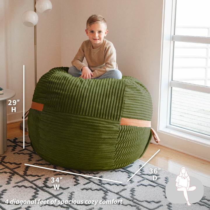 Child sitting on a green bean bag chair with measurements indicated #color_moss-green-corded-plush