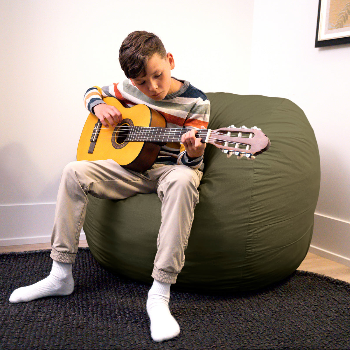 Person playing a guitar on a large green bean bag chair. 