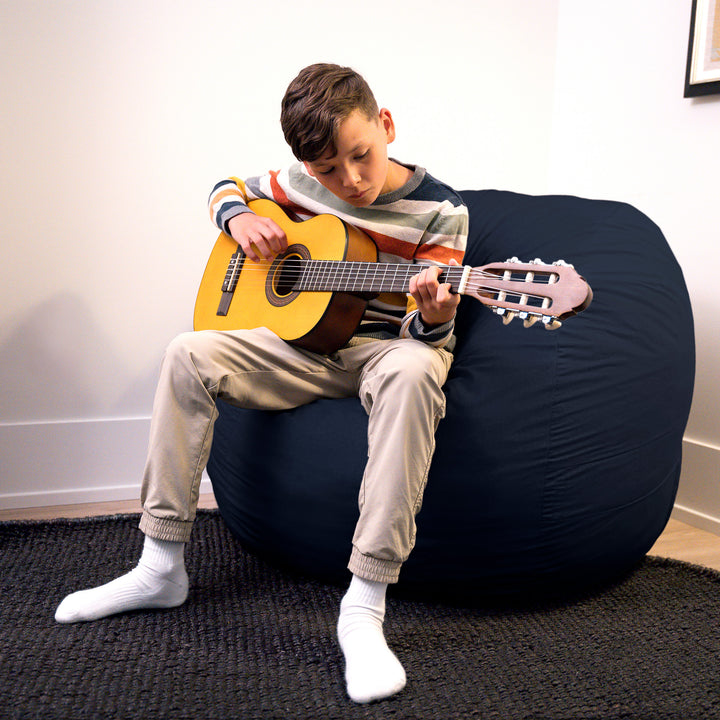 Child playing a guitar on a large navy bean bag chair. #color_cobalt-brushed-denim