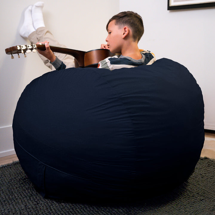 Child playing guitar on a large navy bean bag chair in a room. #color_cobalt-brushed-denim