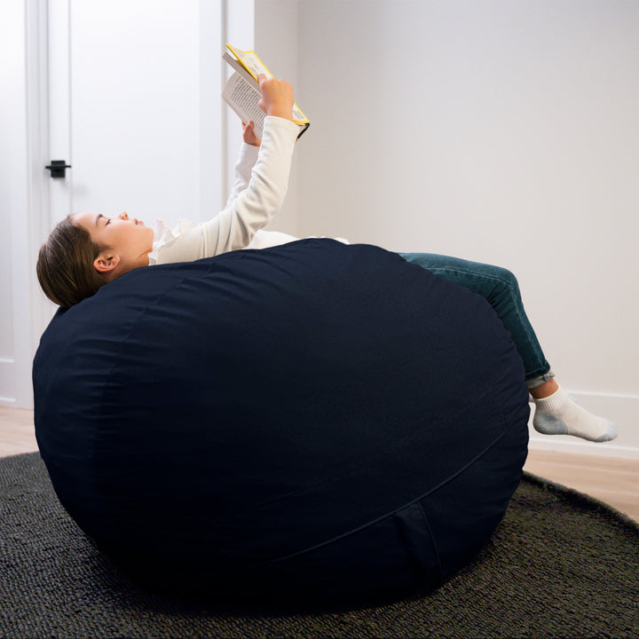 Person lying on a navy bean bag reading a book in a room with white walls. #color_cobalt-brushed-denim