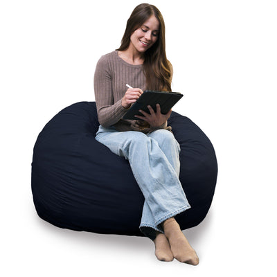Woman sitting on a navy bean bag chair using a tablet. 