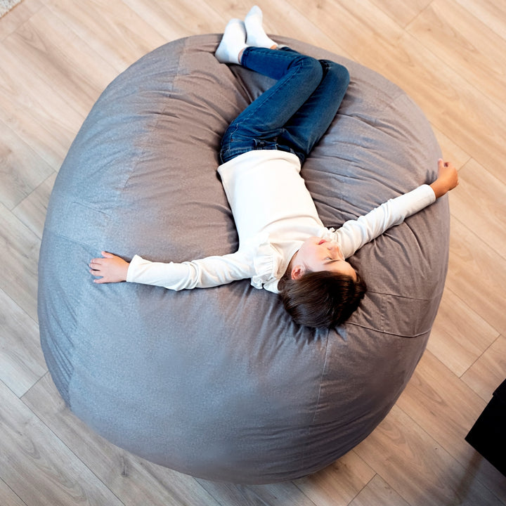 Person lying on a large gray bean bag chair on a wooden floor #color_fog-brushed-denim