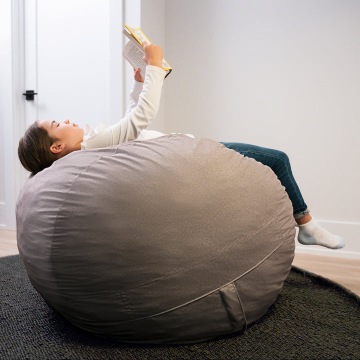 Person reading a book on a large gray bean bag chair in a room. #color_fog-brushed-denim
