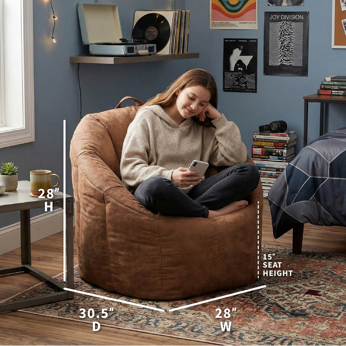 Woman sitting on a brown bean bag chair in a room with shelves and decor. 