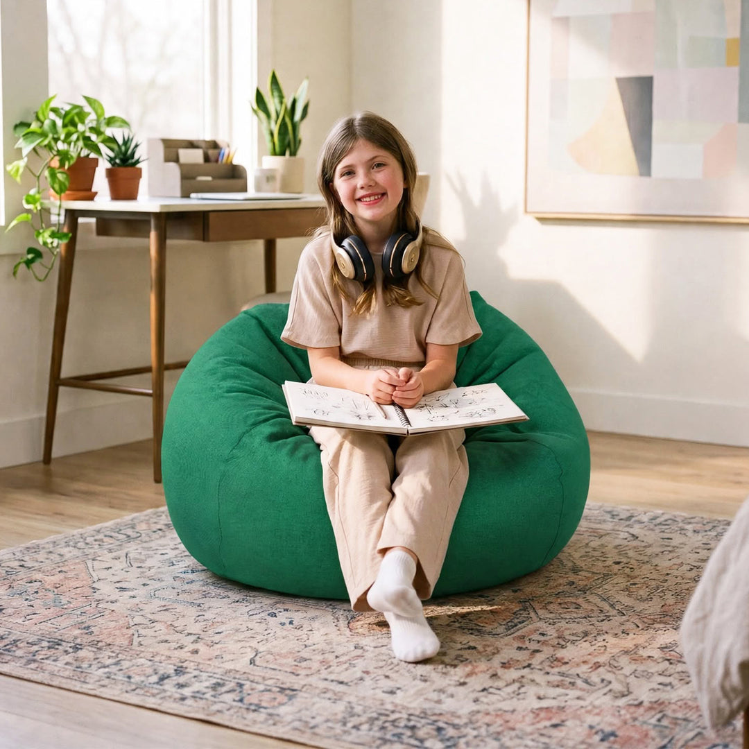 A young girl sits smiling on a large green bean bag chair in a bright, modern room. She is wearing a beige t-shirt and matching pants, with headphones around her neck and an open book in her lap. #color_vibrant-green-everyday-play