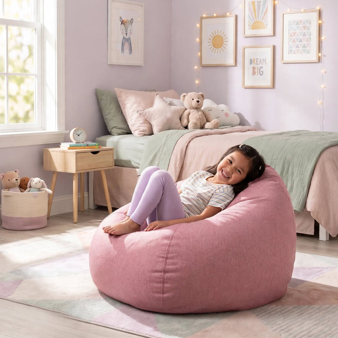 A young girl smiling while reclining on a large dusty pink fabric bean bag chair in a cozy, pastel-colored bedroom. 