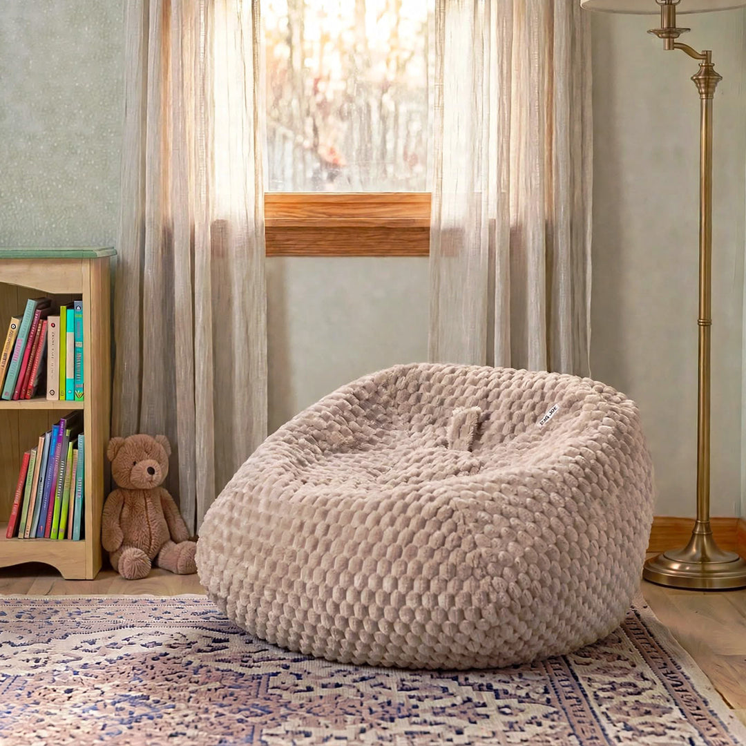 A large, round, textured beige bean bag chair in a cozy child&