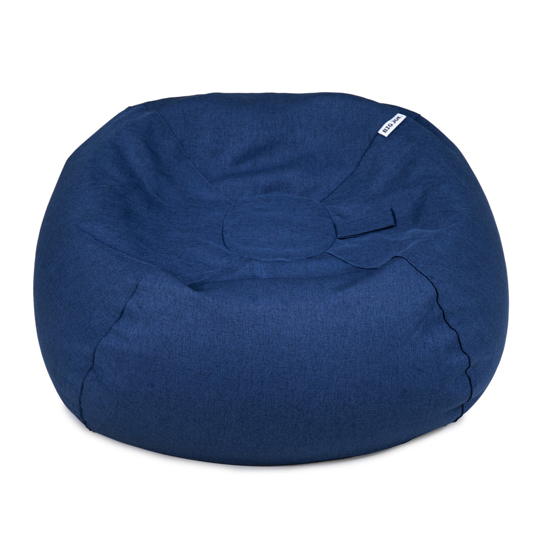 A round navy blue fabric bean bag chair with a small white brand tag on the upper right side, photographed against a solid white background. 