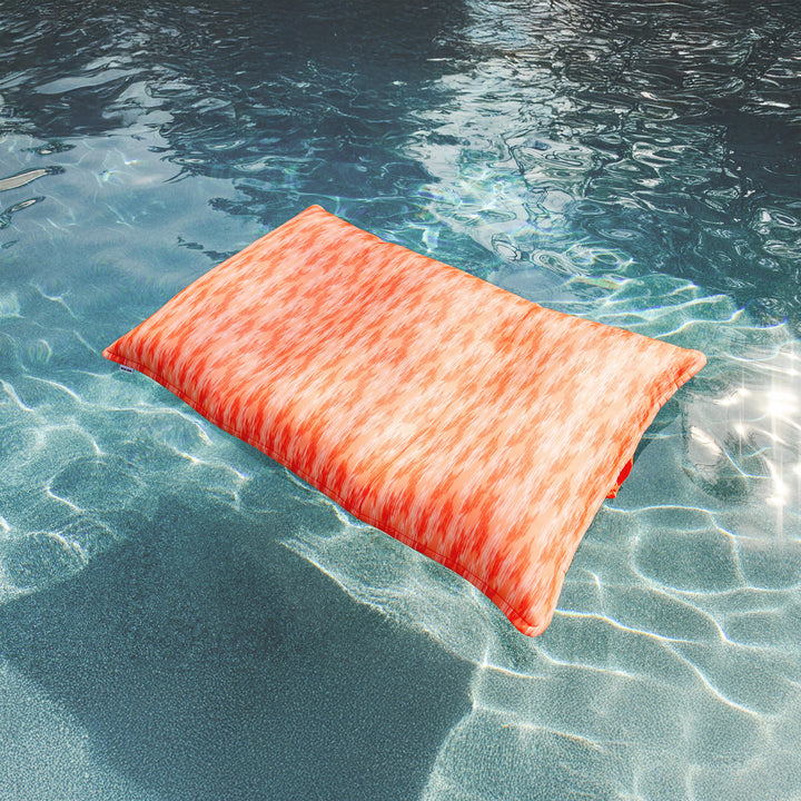 Orange pool floatie floating on clear blue water #color_peach-glow