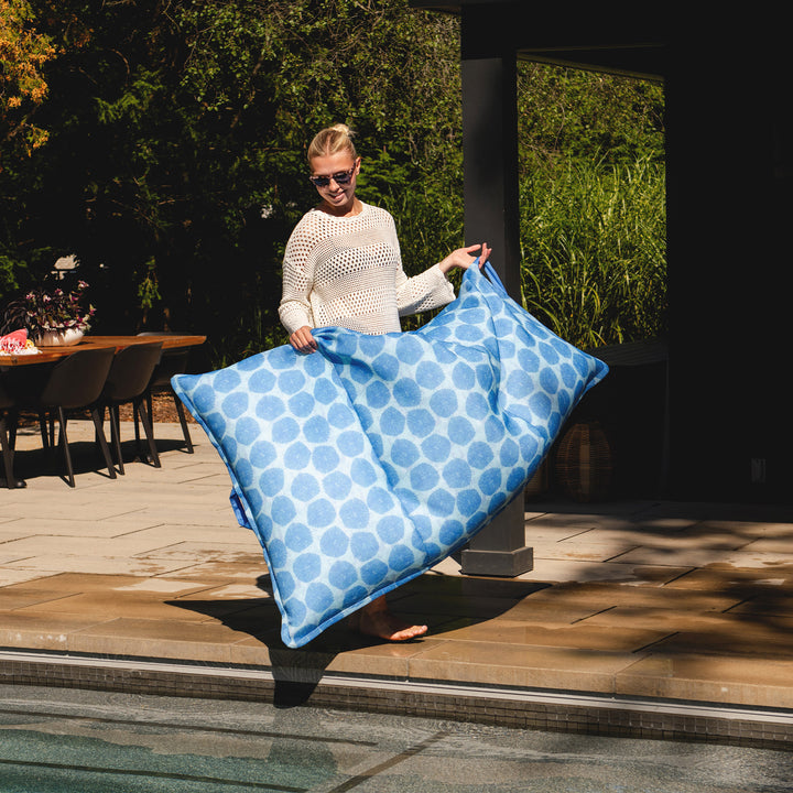Woman holding a blue polka dot pillow float on a patio #color_coral-bloom