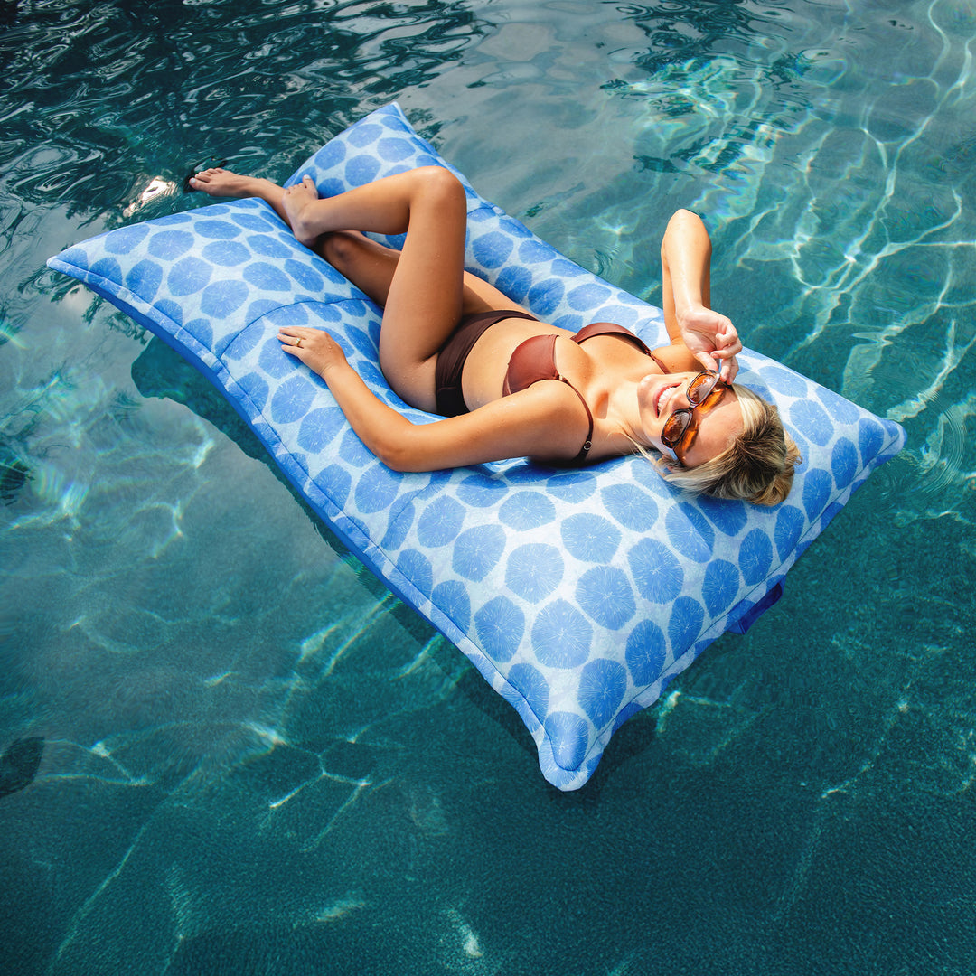 Woman relaxing on a blue pool float in clear water #color_coral-bloom