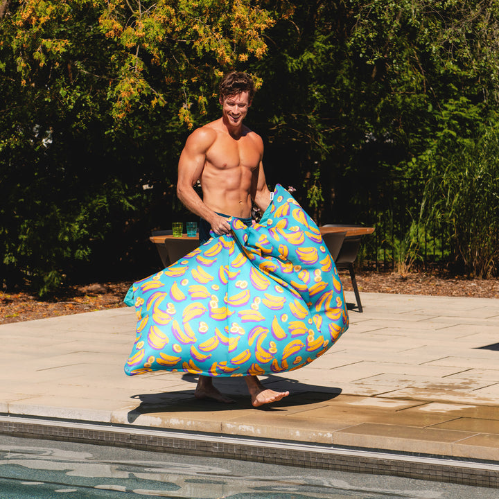 Man holding a colorful pool toy by a pool outdoors #color_banana-pop