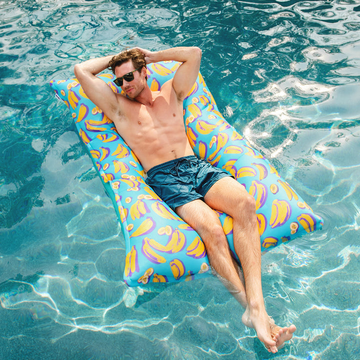 Man relaxing on a colorful pool float in clear blue water #color_banana-pop