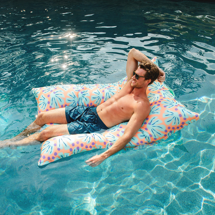Man lying on a colorful pool float in a pool #color_sweet-shells-peach