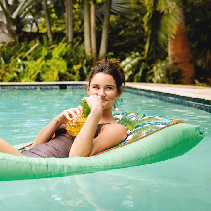 Kona Pool Lounger woman relaxing in pool #color_green-tropical-palm