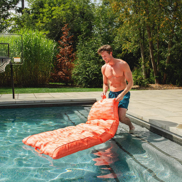 Man with an orange pool float by a pool #color_peach-glow