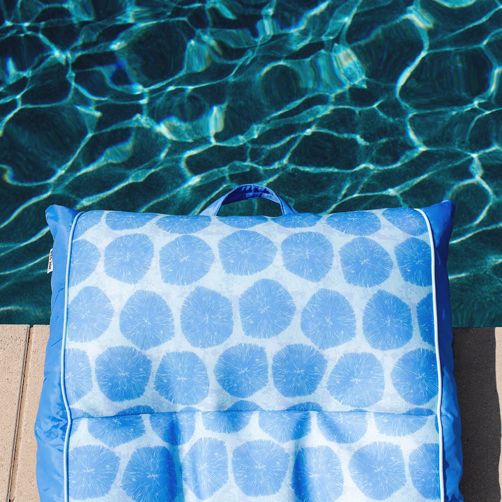 Blue patterned pool float on a ledge by a pool #color_coral-bloom